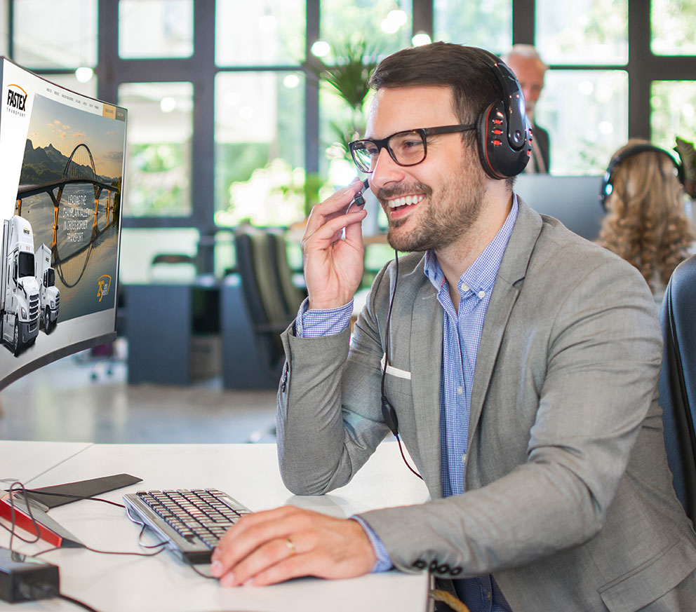 A customer service representative talking on a headset, looking at a computer screen.